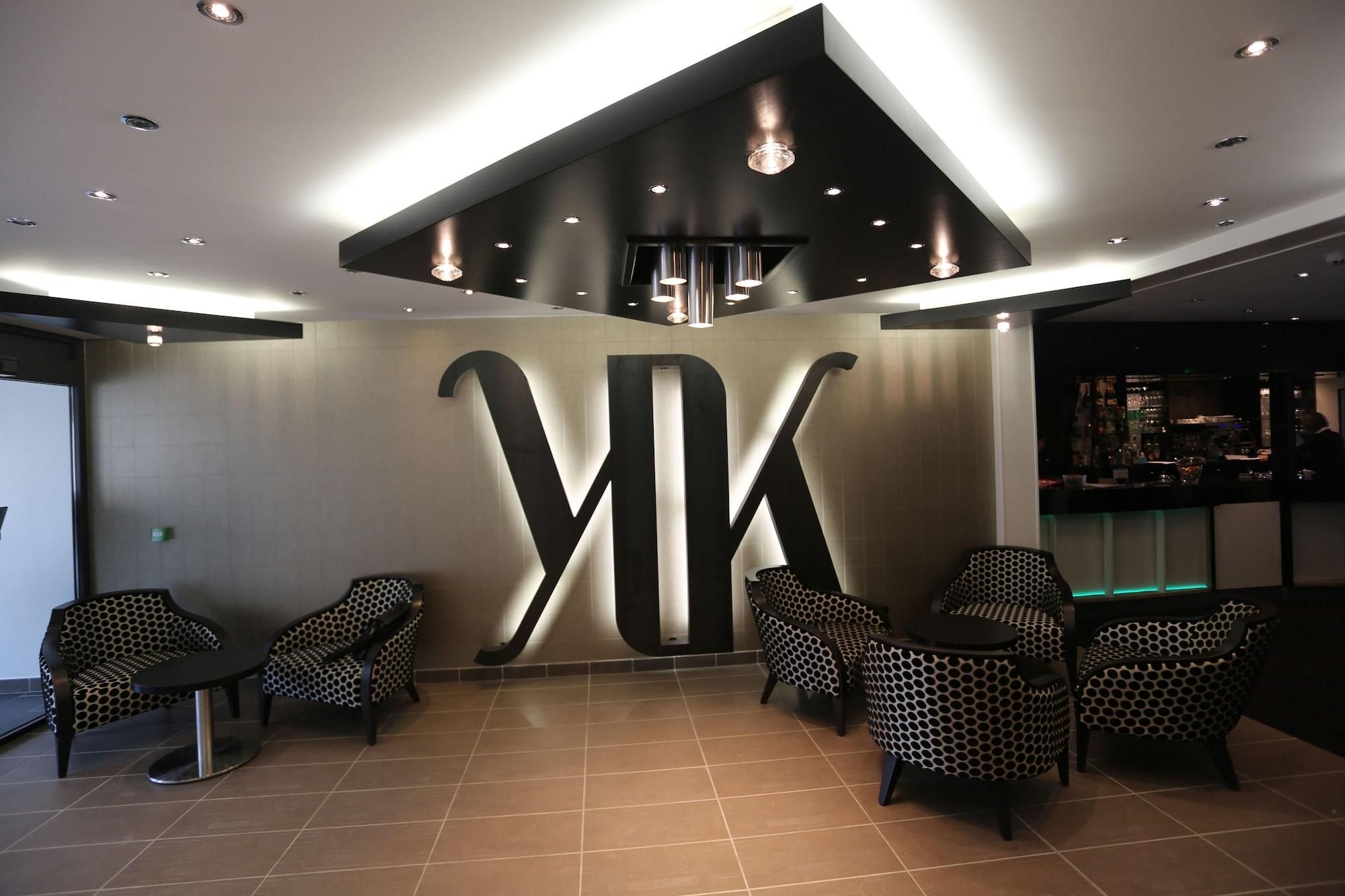 Un intérieur moderne agrémenté d’un grand panneau « VK », de fauteuils à motifs et d’un espace bar.
