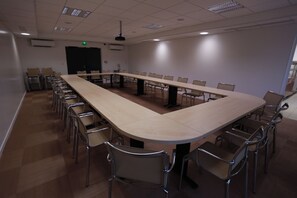 Une salle de conférence avec une longue table, des chaises et un ventilateur de plafond.