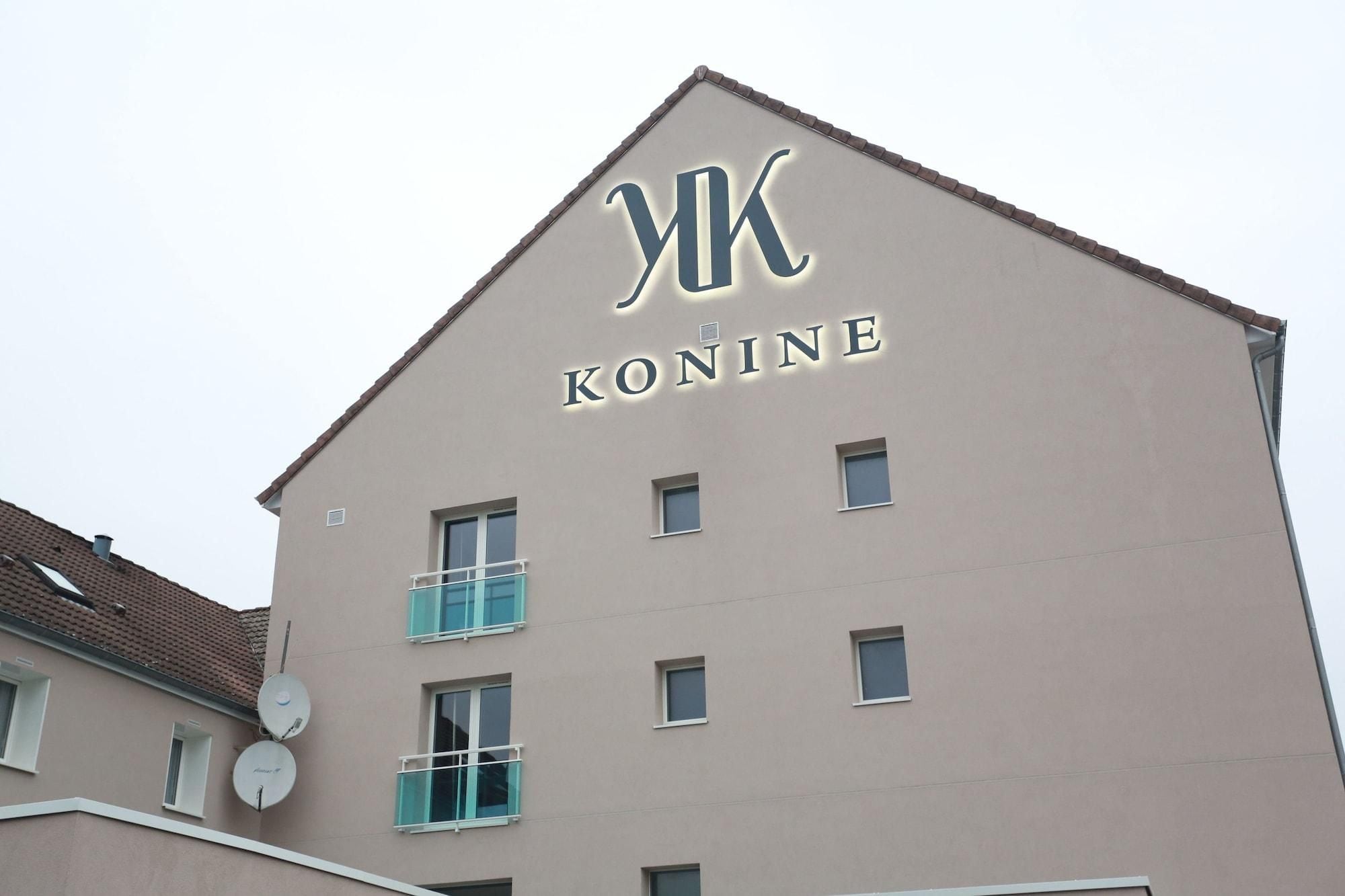 Een gebouw met een bord waarop 'KONINE' staat en een puntig dak.