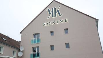 Een gebouw met een bord waarop 'KONINE' staat en een puntig dak.