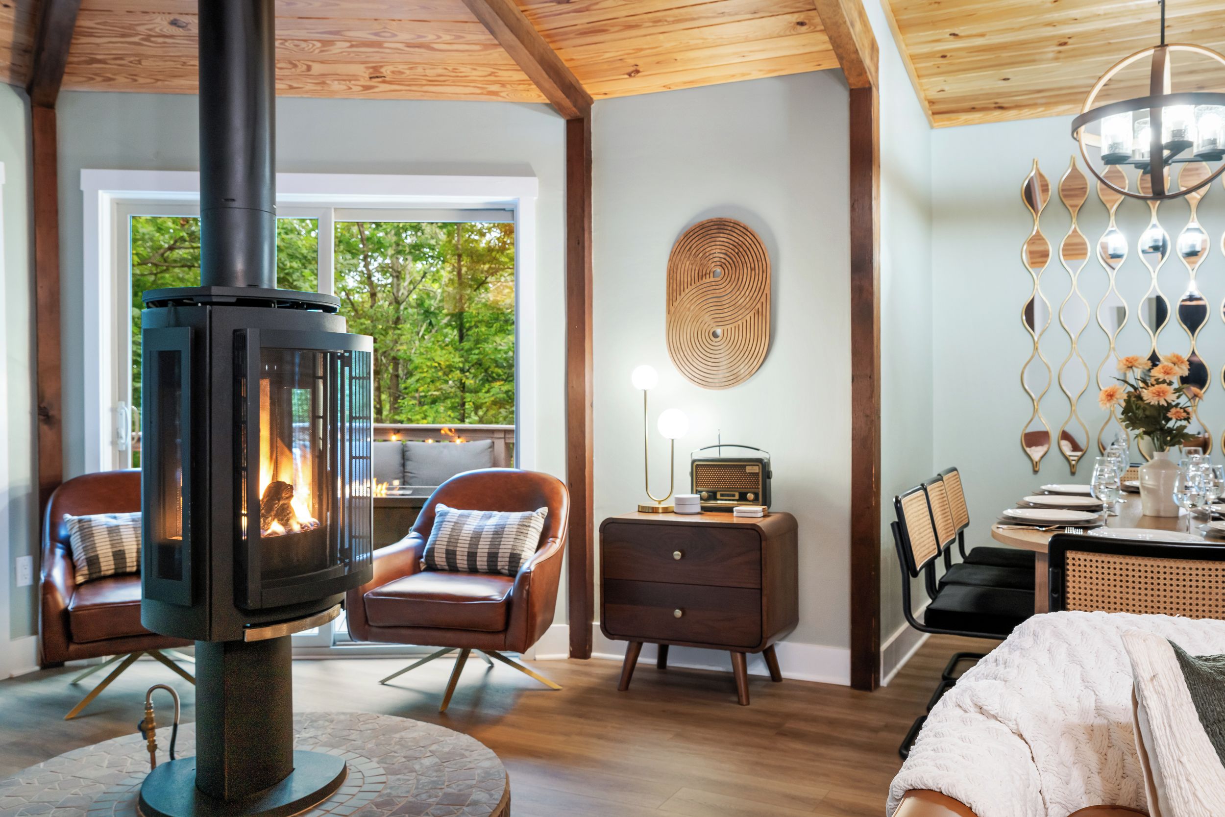 Fireplace seating with leather chairs, warm wood accents, and forest views.