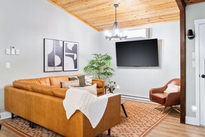 Spacious living room with group seating, large TV, and mid-century style.