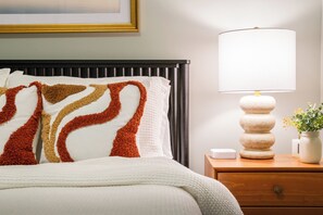 Mid-century nightstand with sculptural lamp and warm rust-and-gold accents.