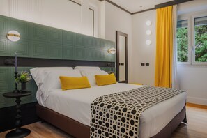 Un dormitorio con cama, lámparas de noche, mesita de noche, ventana con cortinas y vista a zonas verdes.