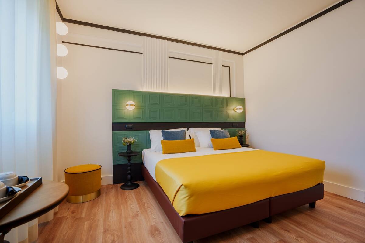 Une chambre d’hôtel moderne avec un grand lit, une petite table ronde et une table de chevet.