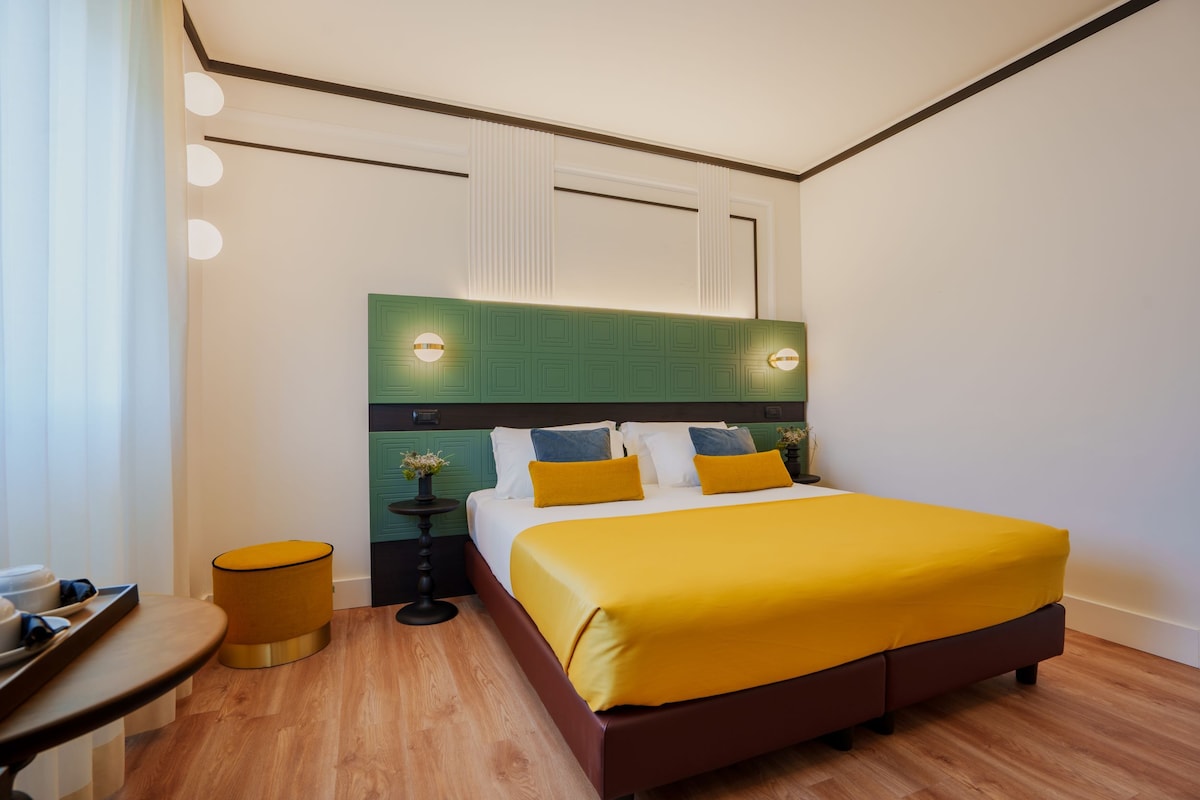 A modern hotel room with a large bed, a small round table, and a nightstand.