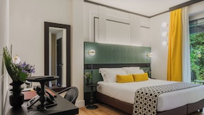 A bedroom with a bed, bedside table, chair, and a desk with a plant.
