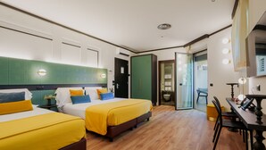 Habitación de hotel con dos camas, una mesa de comedor y un baño con puerta de cristal.