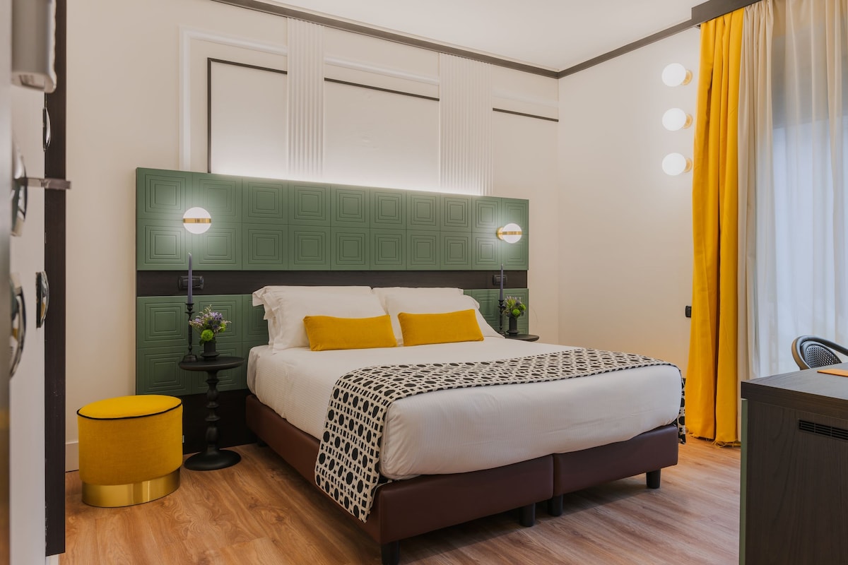 A neatly arranged bedroom with a bed, bedside tables, a green headboard, and a yellow curtain.