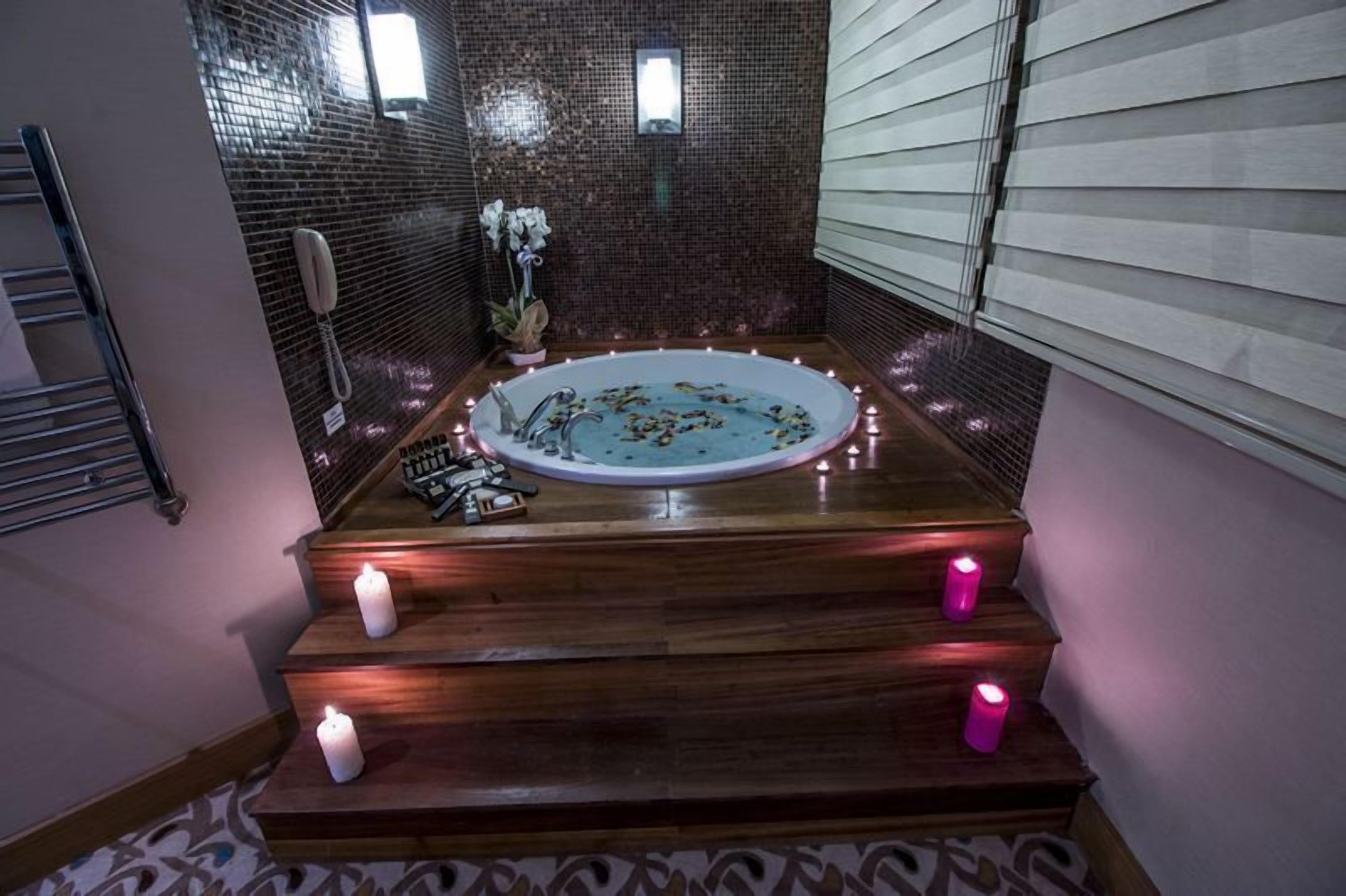 Ein Badezimmer mit einer Holzbadewanne, gefliesten Wänden und einem kleinen Fenster.