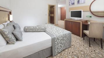 Una habitación de hotel con una cama, un escritorio con una computadora, un televisor y una silla.