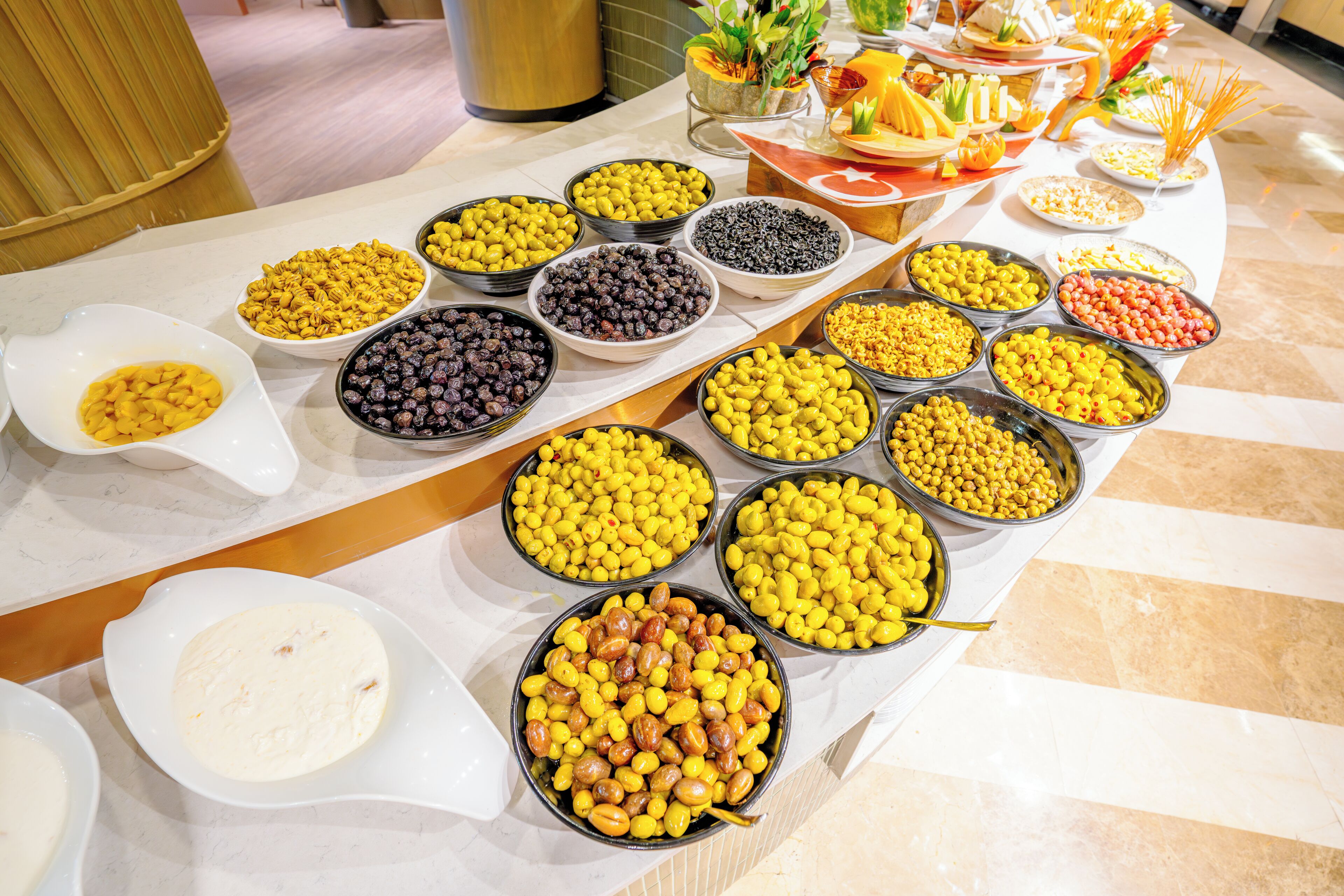 Una mesa de buffet con diversos alimentos, incluyendo tazones de frutos secos, frutas y otras botanas.