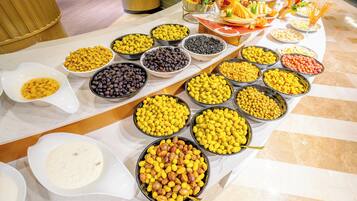 Una mesa de buffet con diversos alimentos, incluyendo tazones de frutos secos, frutas y otras botanas.