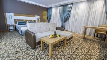 Une chambre d’hôtel avec un canapé, une petite table avec des fruits, un lit et un coin repas.