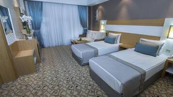 A hotel room with two beds, a wooden dresser, a mirror, and a patterned carpet.