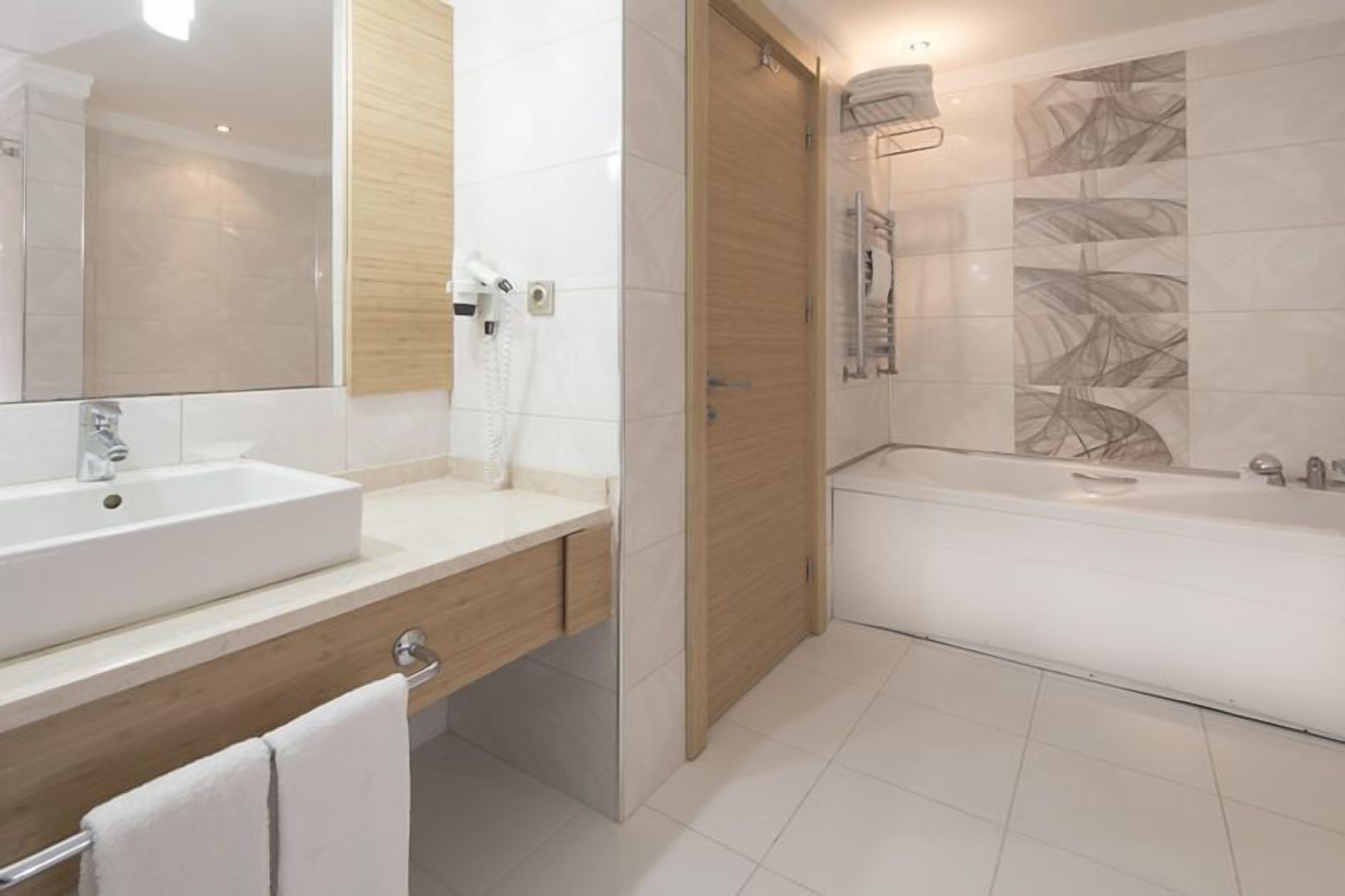 Un baño moderno con un lavamanos grande, un espejo, zona de ducha y un perchero para toallas.
