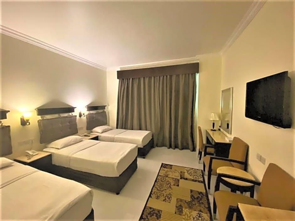 A hotel room with two beds, a desk, a chair, a TV, and a window with curtains.