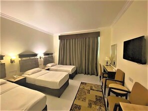 A hotel room with two beds, a desk, a chair, a TV, and a window with curtains. - Signature Inn Hotel Free Parking (Dubai)