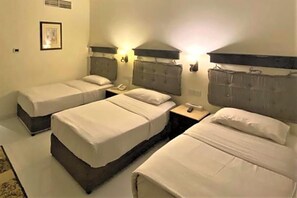 A hotel room with two single beds, a nightstand with a phone, and a framed picture on the wall. - Signature Inn Hotel Free Parking (Dubai)