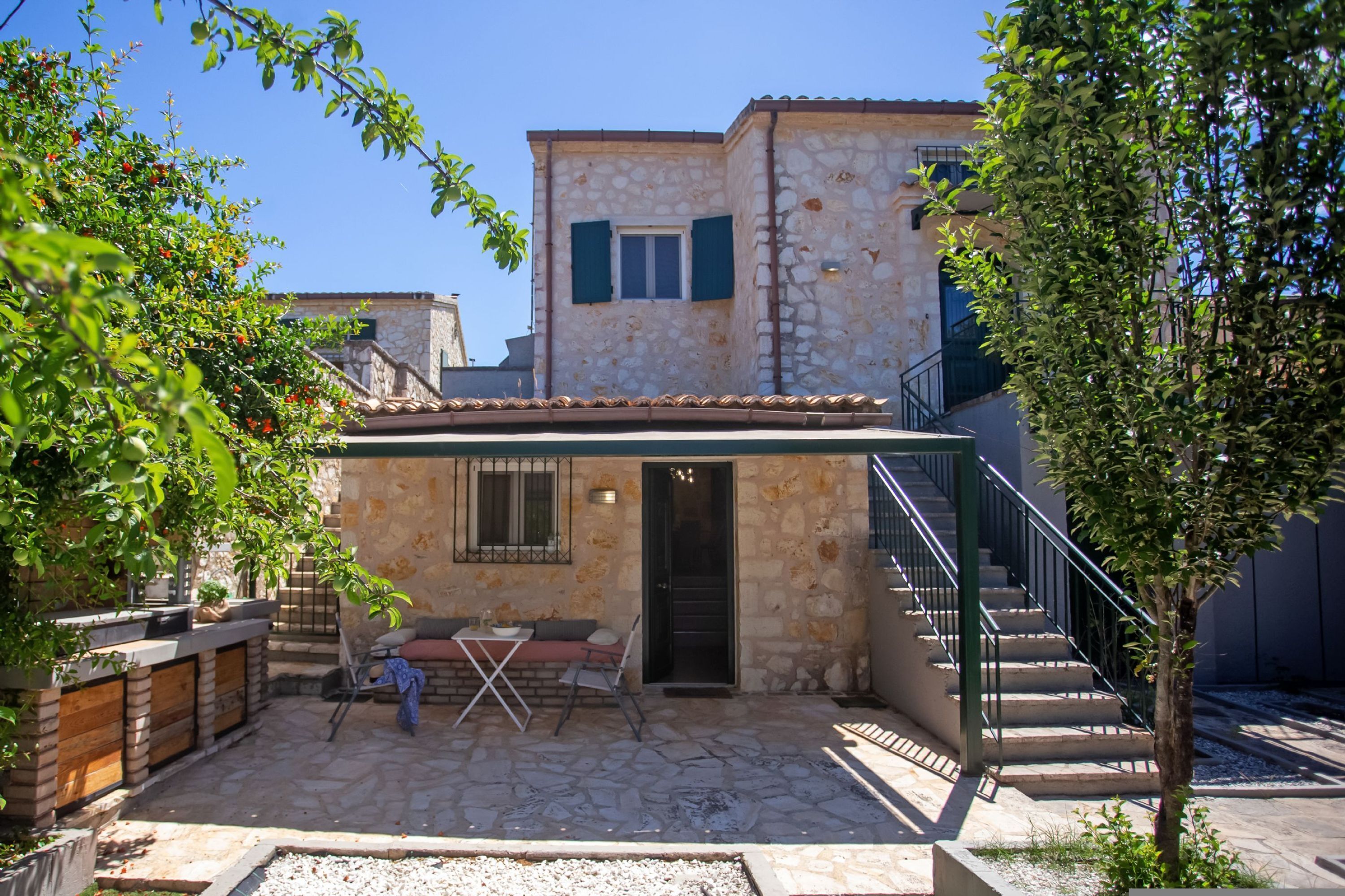 Un bâtiment en pierre doté d’un patio, d’un espace extérieur aménagé pour s’asseoir et d’un escalier menant à un niveau supérieur.