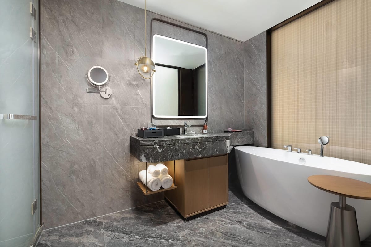 A modern bathroom with a freestanding bathtub, a vanity with a mirror, and a towel rack.