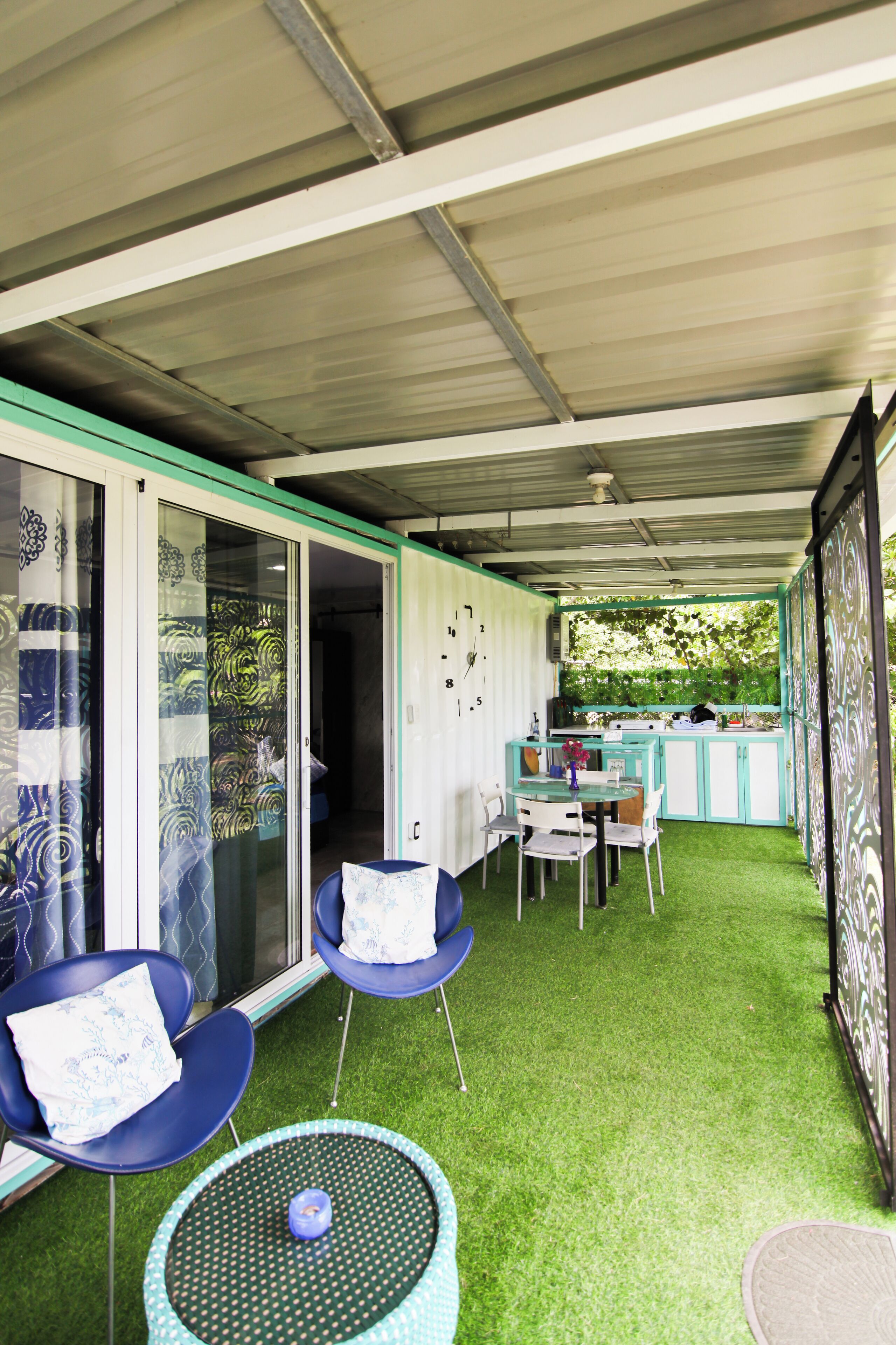 A covered outdoor area with a dining table, chairs, and a small round table with a candle.