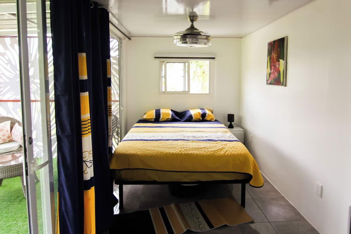 A bedroom with a bed, a window, and a door leading to a balcony.