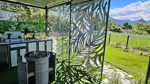 Un balcone con angolo cottura, dotato di fornelli, lavello e sedie.