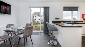 Eine moderne Küche mit Essbereich, einem an der Wand montierten Fernseher und Blick ins Freie.