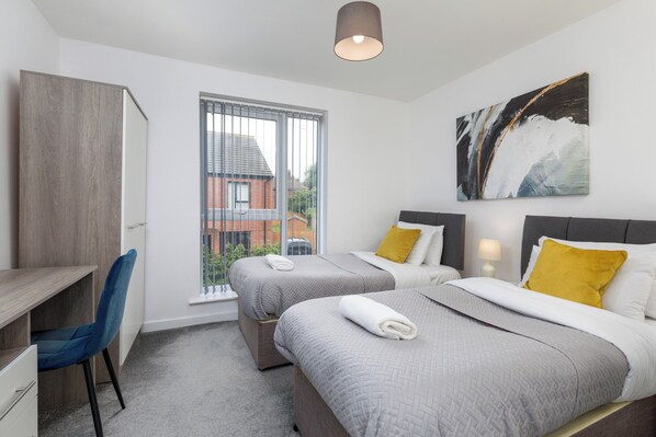 Une chambre d’hôtel moderne avec deux lits, un bureau et une chaise.