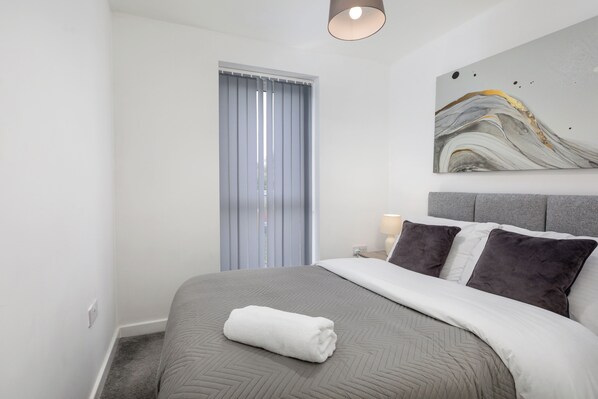Habitación de hotel moderna con una cama grande, vista de la ciudad a través de la ventana y un cuadro abstracto contemporáneo en la pared.