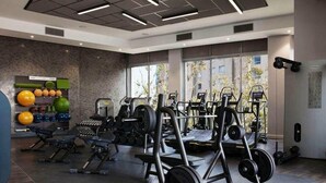 Ein modernes Fitnessstudio mit Kraftgeräten, einer Wand voller Sportbälle und großen Fenstern.