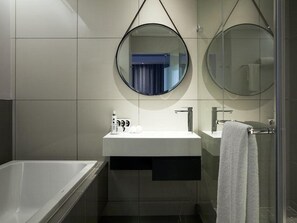 A modern bathroom with a bathtub, a sink with a mirror, and a towel rack.