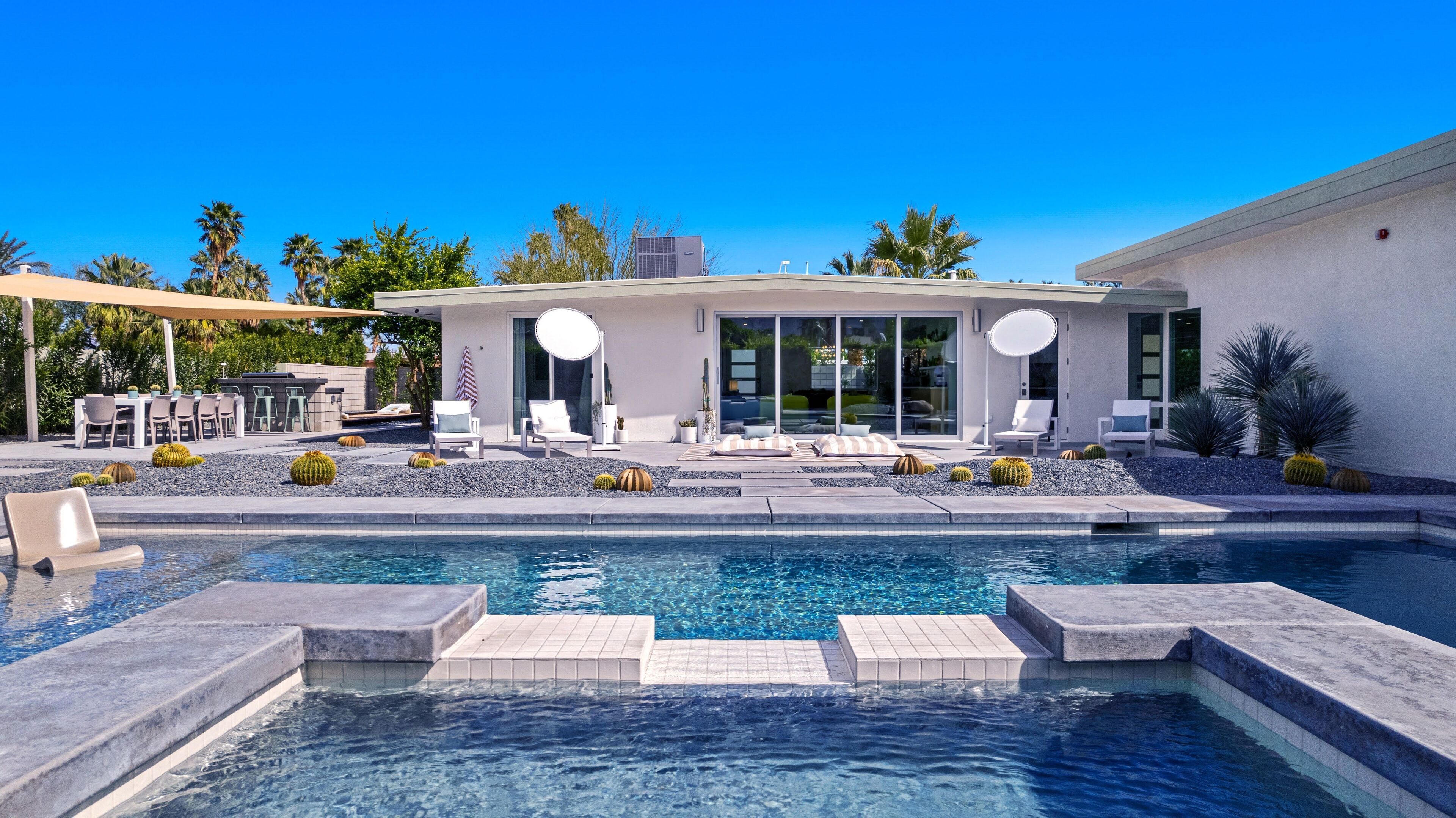 A modern house with a swimming pool, outdoor seating, and a patio area.