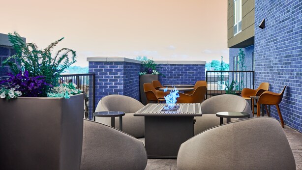 An outdoor seating area with a table and chairs, a fire feature, and a brick wall. - SpringHill Suites by Marriott St. Louis Chesterfield (Chesterfield)
