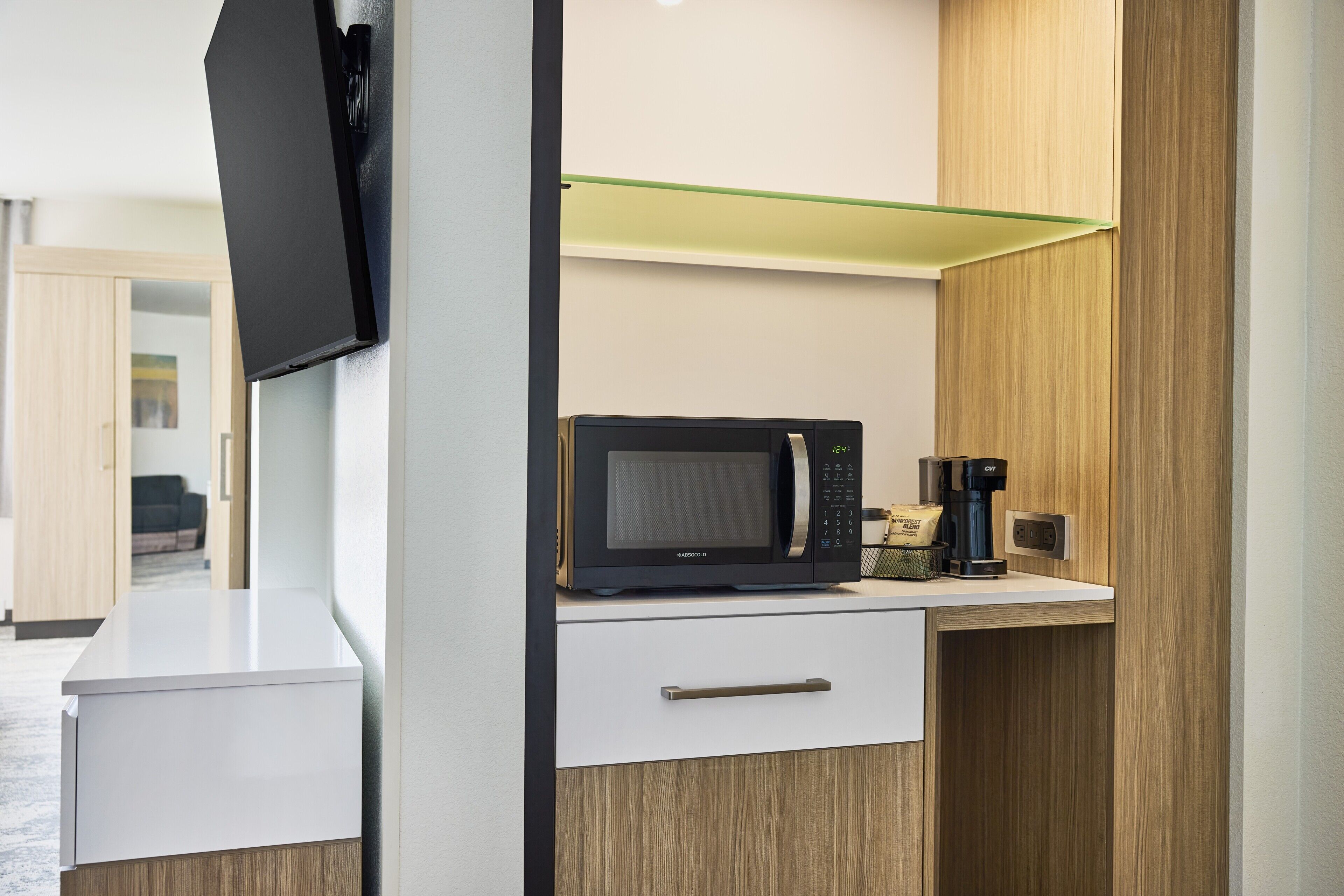 Eine moderne Küche mit Mikrowelle, Kaffeemaschine und einer Glasablage.