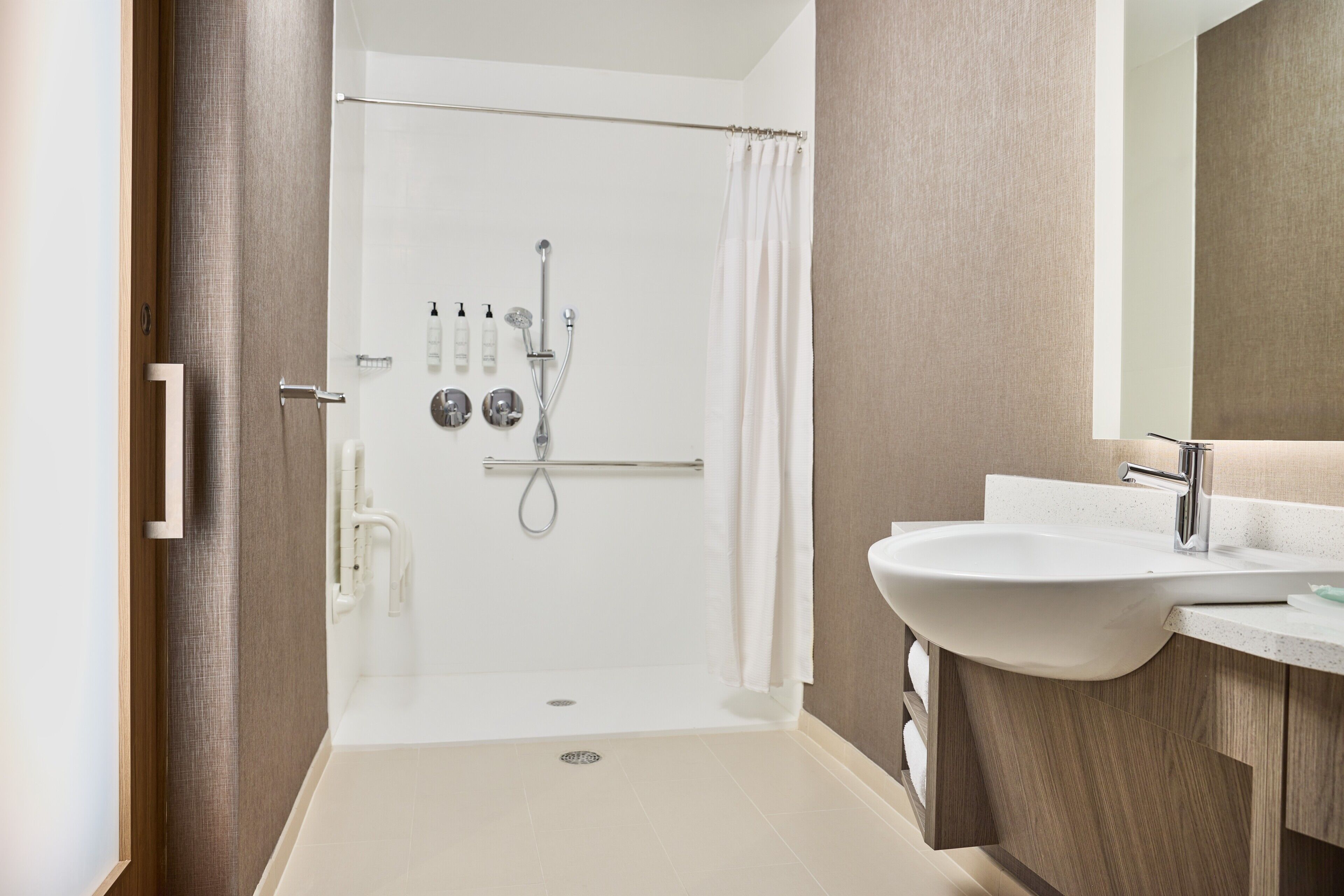 A modern bathroom with a walk-in shower, a sink, and a mirror.