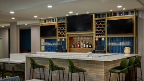 A bar area with a counter, stools, and shelves with bottles and glasses. - SpringHill Suites by Marriott St. Louis Chesterfield (Chesterfield)
