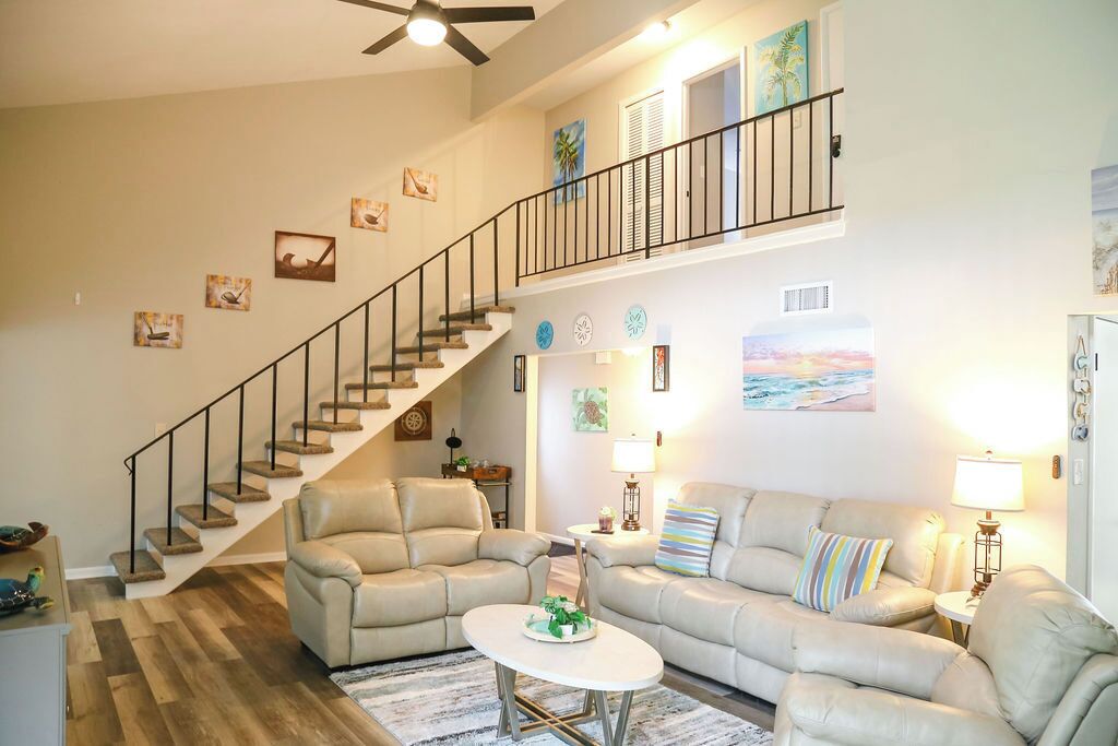 A spacious living room with a staircase, two sofas, a coffee table, and wall art.