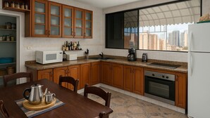 A kitchen with wooden cabinets, a microwave, a coffee maker, and a refrigerator. - PH Recoletos (Caracas)