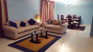 A living room with two sofas, a glass coffee table, and a dining area with a table and chairs. - PH Recoletos (Caracas)