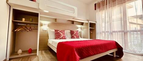 A bedroom with a bed, a wardrobe, and a window with curtains.