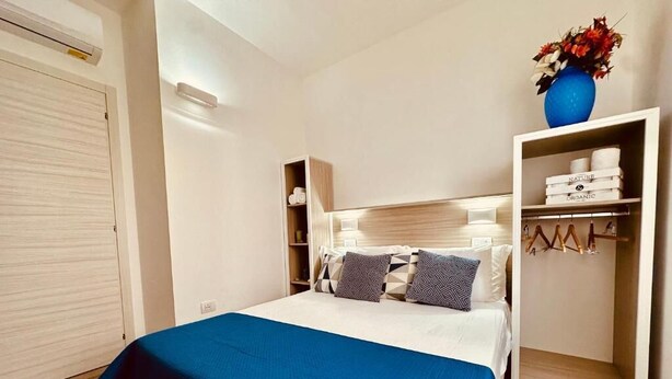 A bedroom with a bed, a wardrobe, and a shelf with toiletries. - B&B THE SEA - Family Rooms (Tropea)