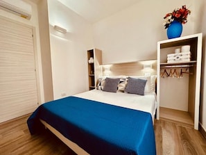A bedroom with a bed, a wardrobe, and a shelf with toiletries. - B&B THE SEA - Family Rooms (Tropea)