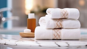 A stack of white towels with a plaid pattern on a marble surface, a wooden bowl, and a bottle of soap in a bathroom setting. - B&B THE SEA - Family Rooms (Tropea)