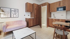 Een moderne keuken met houten kastjes, een ingebouwde magnetron en een eethoek met een tafel en stoelen.