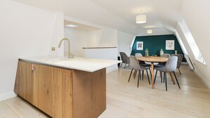 Een moderne keuken met een houten kookeiland, een eethoek met tafel en stoelen, en uitzicht op de woonkamer door een open verbinding.