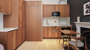 Een moderne keuken met houten kastjes, een magnetron en een eethoek met een tafel en stoelen.