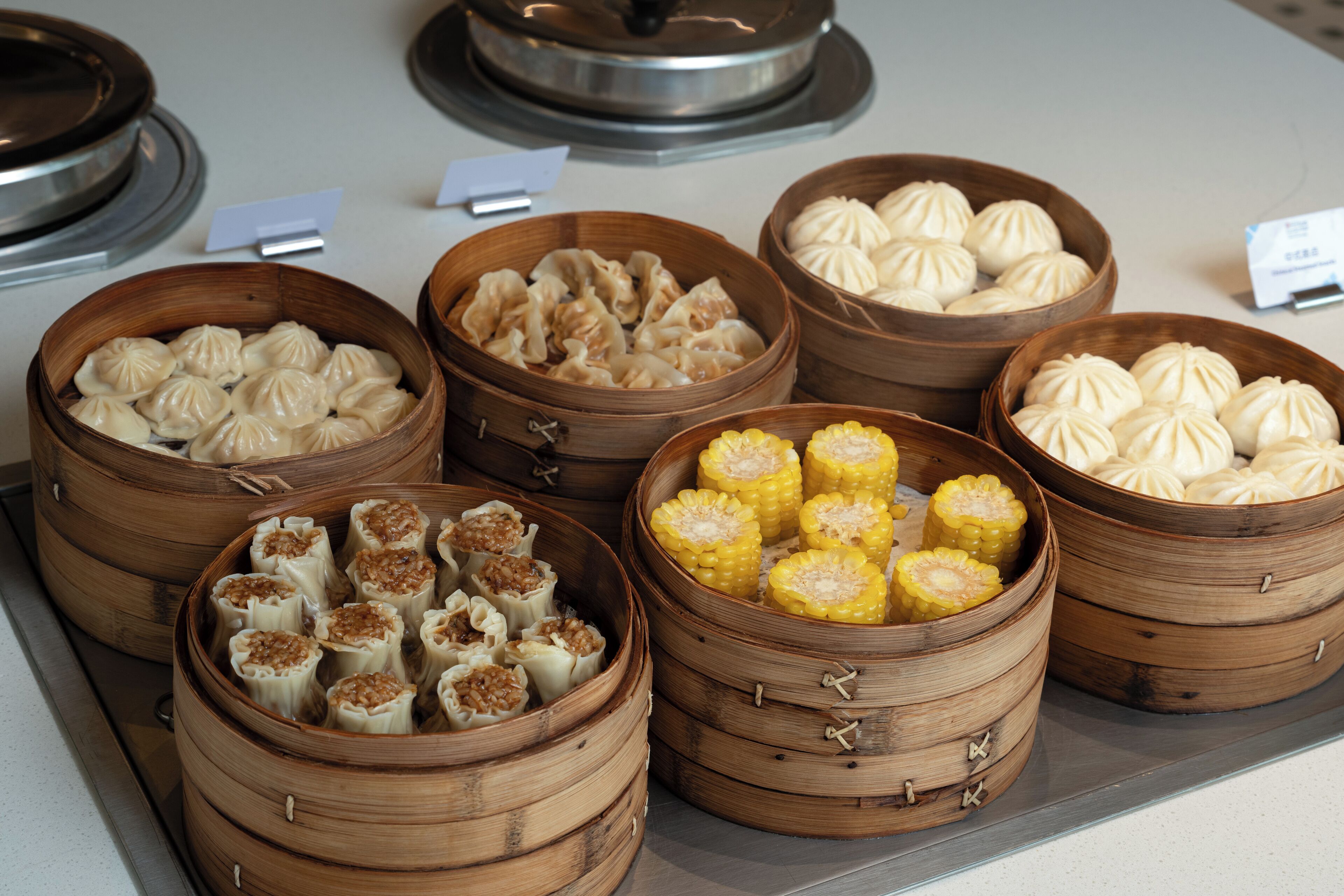A display of various steamed buns in wooden baskets.