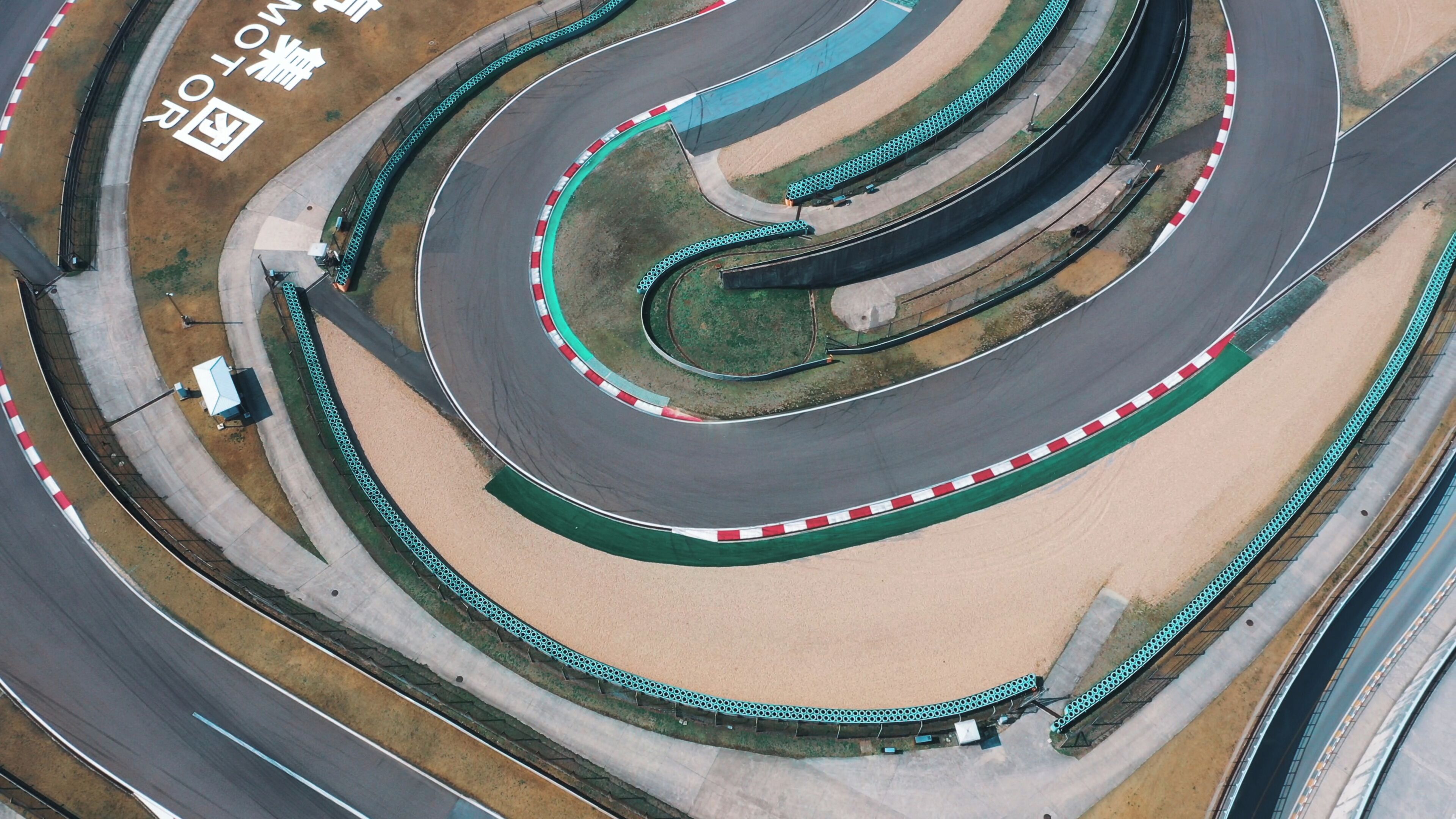 An aerial view of a race track with multiple curves and safety barriers.